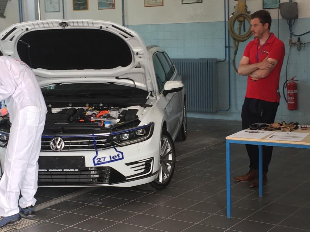 Tekmovalec ob avtomobilu z odprtim pokrovom motorja.
