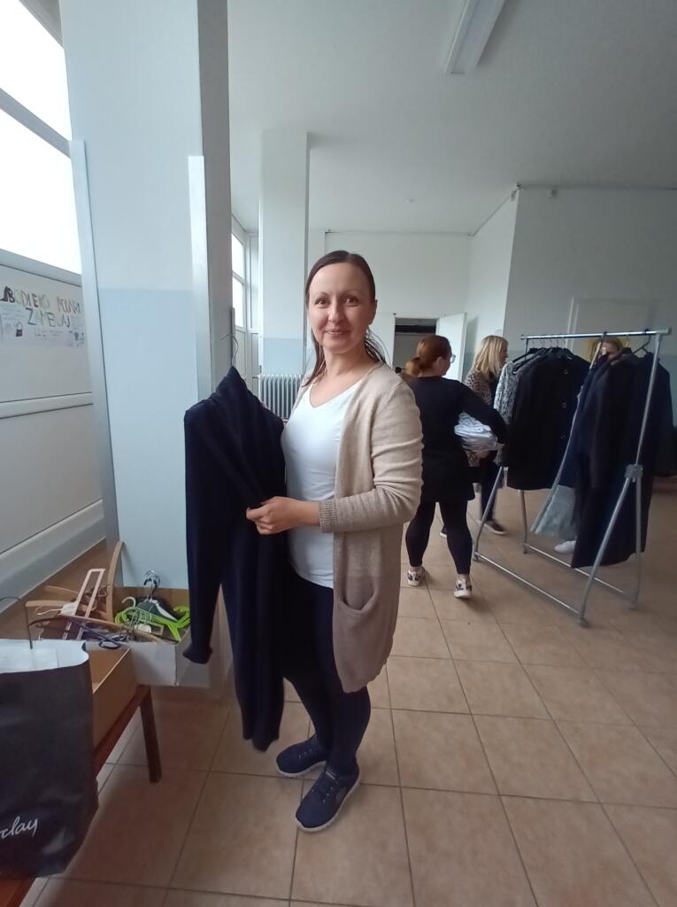Udeleženka drži temen kos oblačila na izmenjevalnici.
