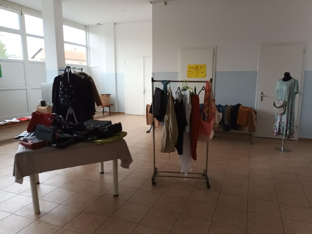 Stojala z oblačili in mize v izmenjevalnici.