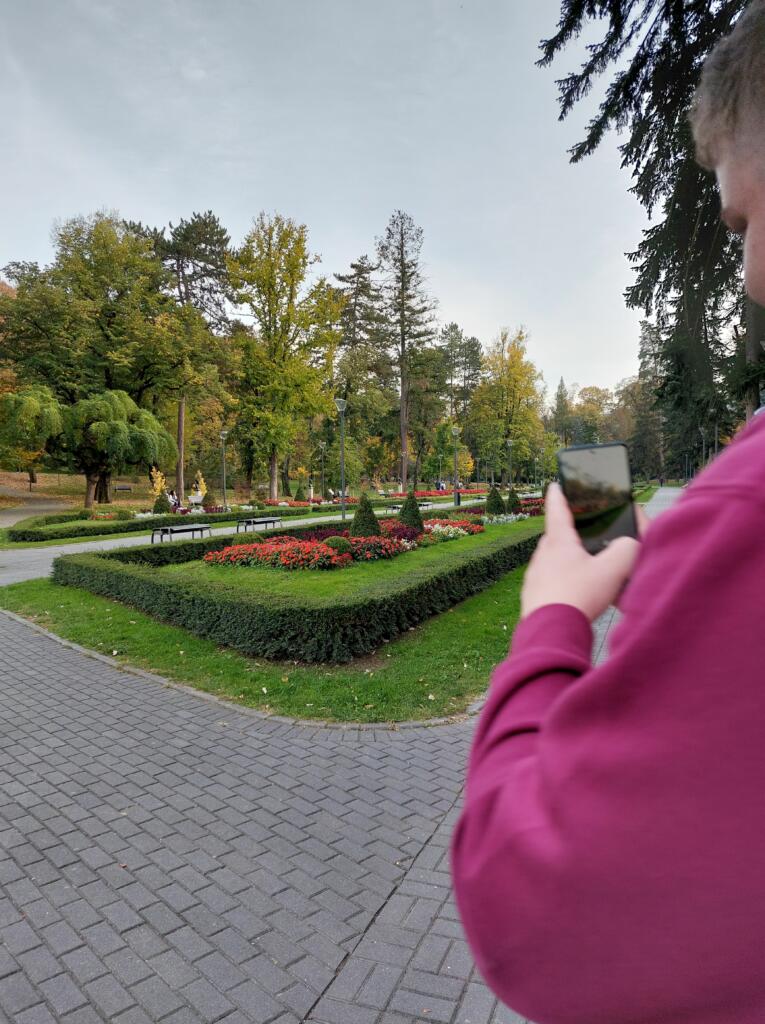 Udeleženci obiska fotografirajo urejen park.