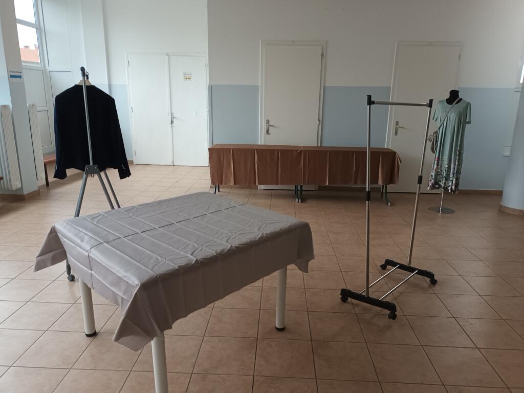 Pripravljen prostor izmenjevalnice z mizami in obešalniki za oblačila.