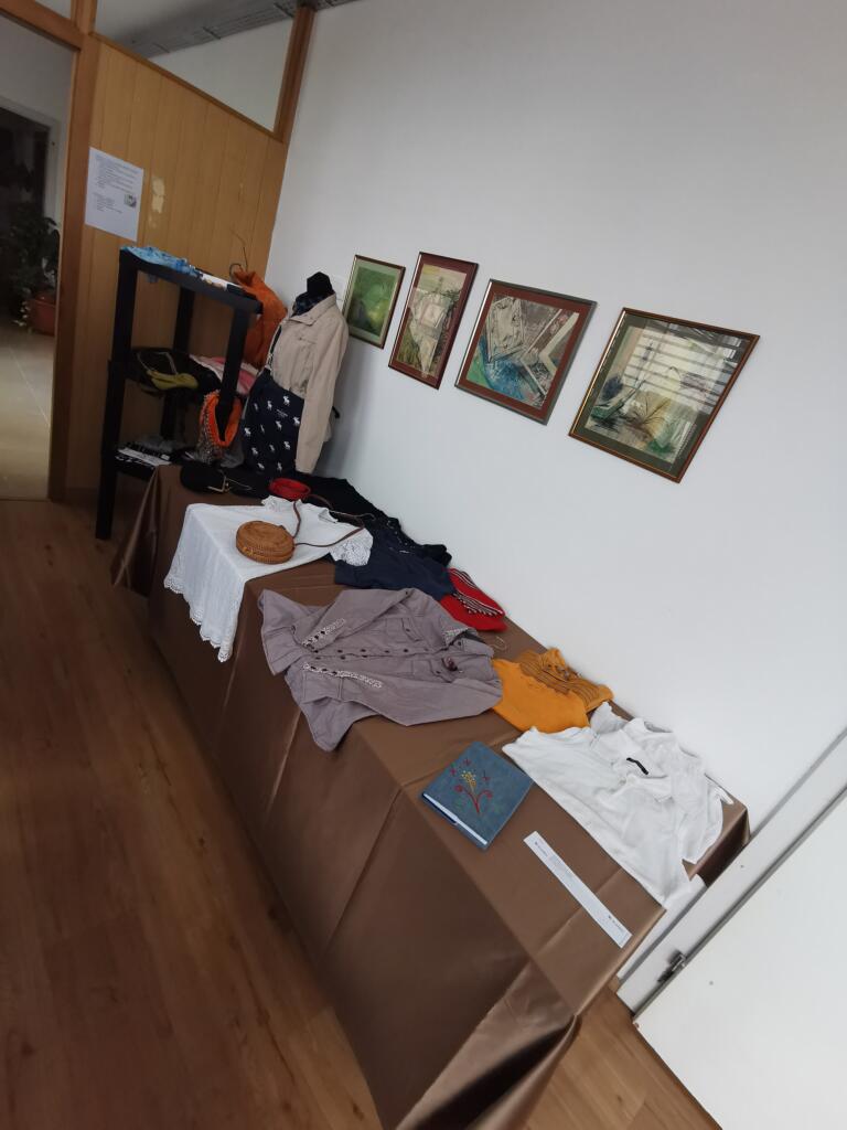 Miza z oblačili ob stenski razstavi v izmenjevalnici.