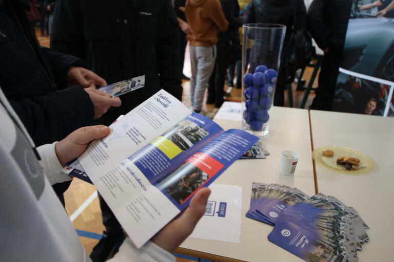 Obiskovalci pregledujejo zloženke in gradivo na predstavitveni stojnici.