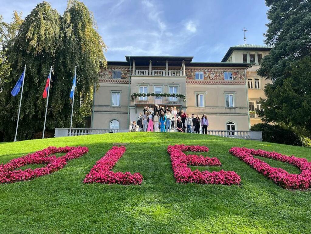 Skupina dijakov pred stavbo s cvetličnim napisom Bled.