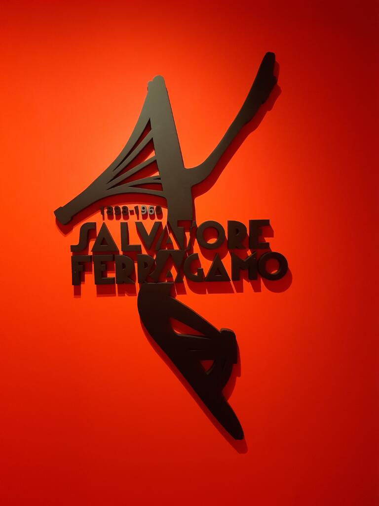 Razstavni napis in čevelj Salvatore Ferragamo na rdečem ozadju.
