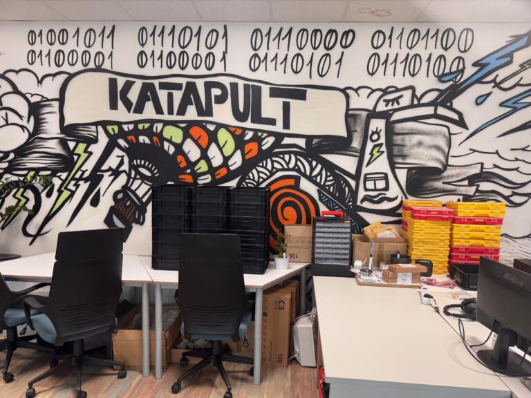 Prostor Katapulta z orodjem in napisom na steni.